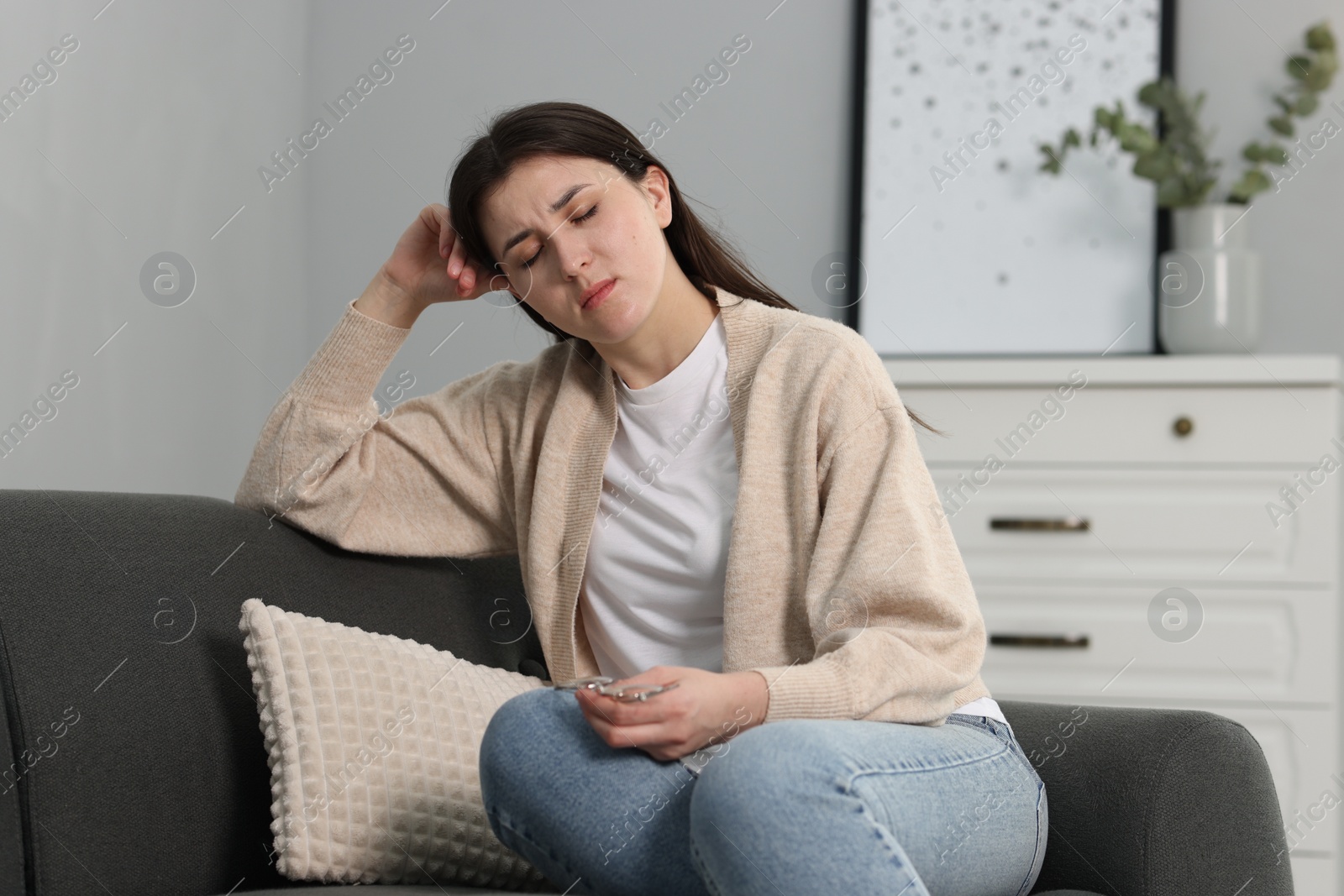 Photo of Overwhelmed woman with glasses sitting on sofa at home