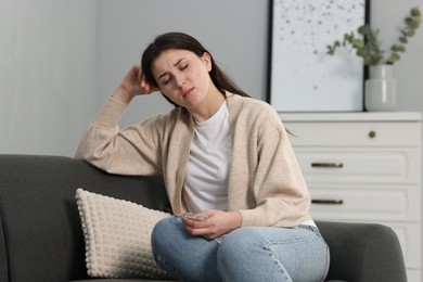 Overwhelmed woman with glasses sitting on sofa at home