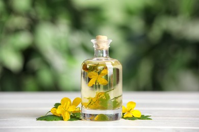 Bottle of celandine tincture and plant on wooden table outdoors