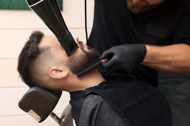 Photo of Professional hairdresser working with client in barbershop, closeup