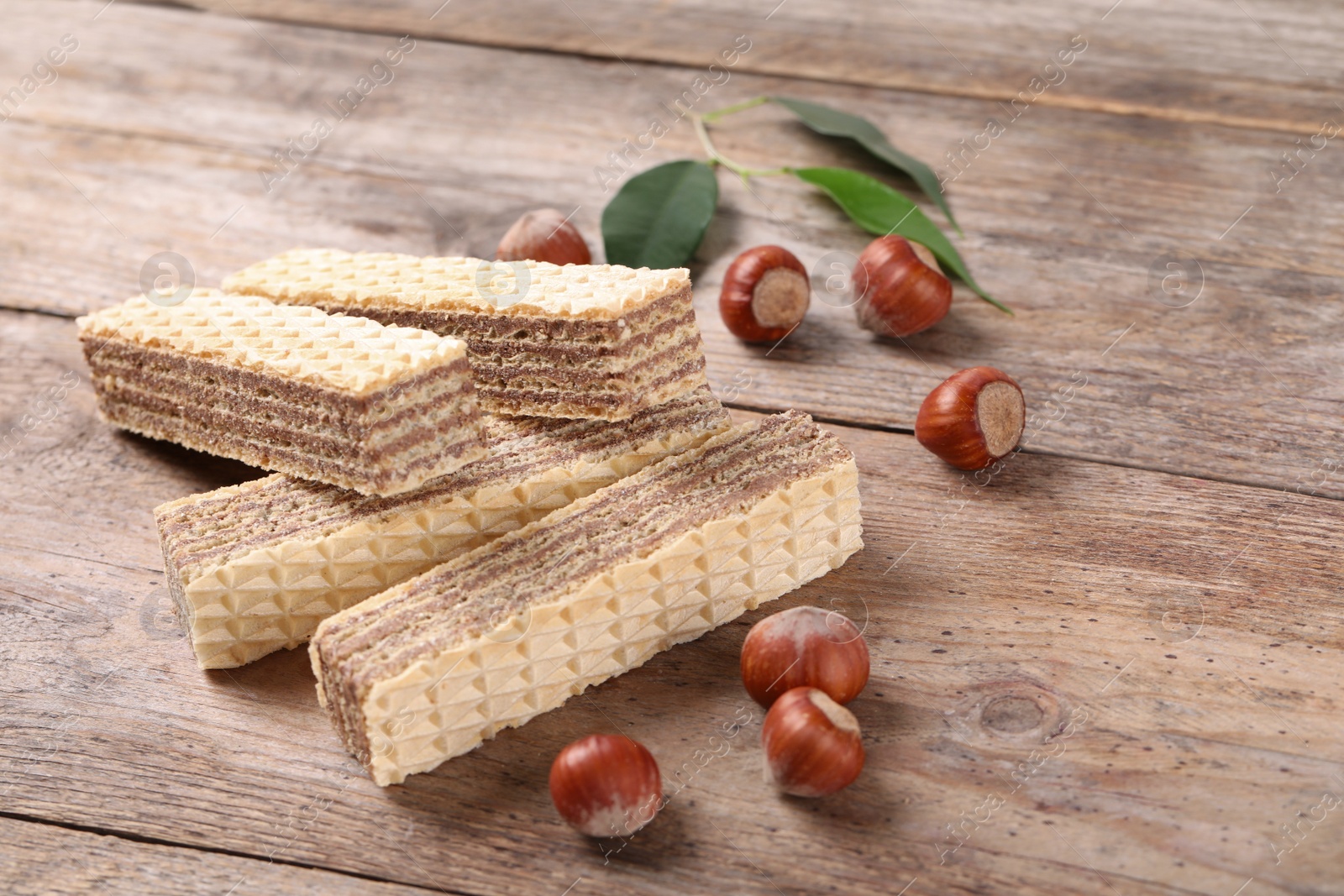 Photo of Delicious wafers with hazelnuts on brown wooden background