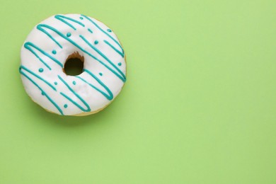 Photo of Tasty glazed donut on green background, top view. Space for text