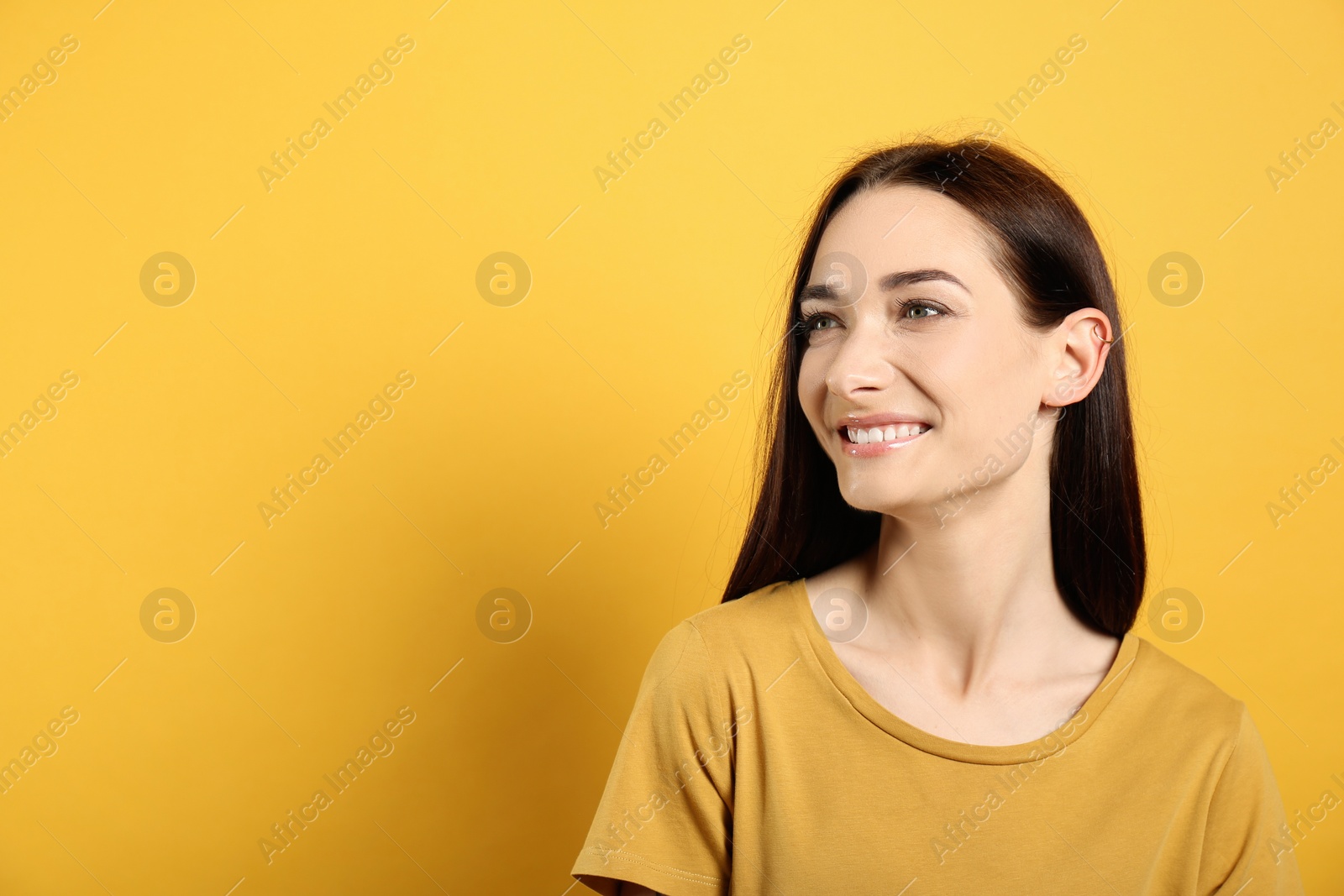 Photo of Portrait of pretty young woman with gorgeous chestnut hair and charming smile on yellow background, space for text