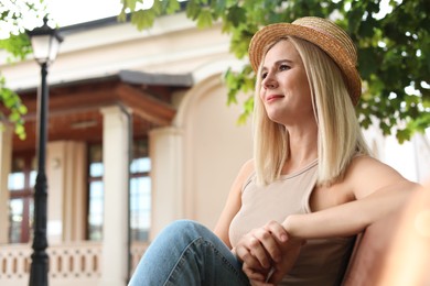 Portrait of beautiful woman in straw hat on city street