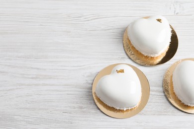 Photo of St. Valentine's Day. Delicious heart shaped cakes on white wooden table, flat lay. Space for text