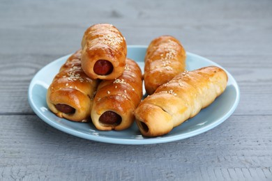 Photo of Delicious sausage rolls on grey wooden table