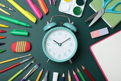 Photo of Flat lay composition with alarm clock and different stationery on green chalkboard. School time