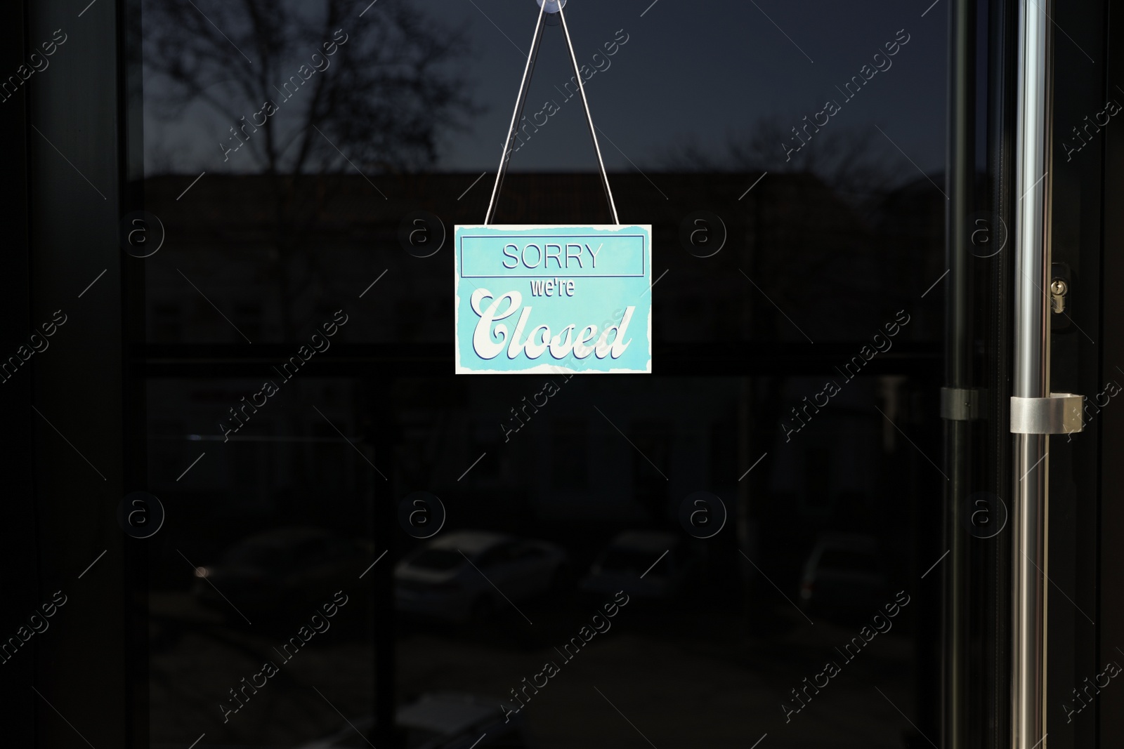 Photo of Light blue sign with text Sorry we're Closed hanging on glass door. Coronavirus quarantine