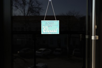 Photo of Light blue sign with text Sorry we're Closed hanging on glass door. Coronavirus quarantine