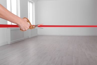 Photo of Woman cutting red ribbon on blurred background. Festive ceremony