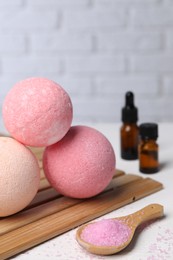 Beautiful aromatic bath bombs and sea salt on white table, closeup. Space for text