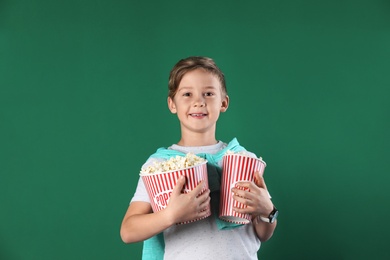 Photo of Cute boy with popcorn buckets on color background