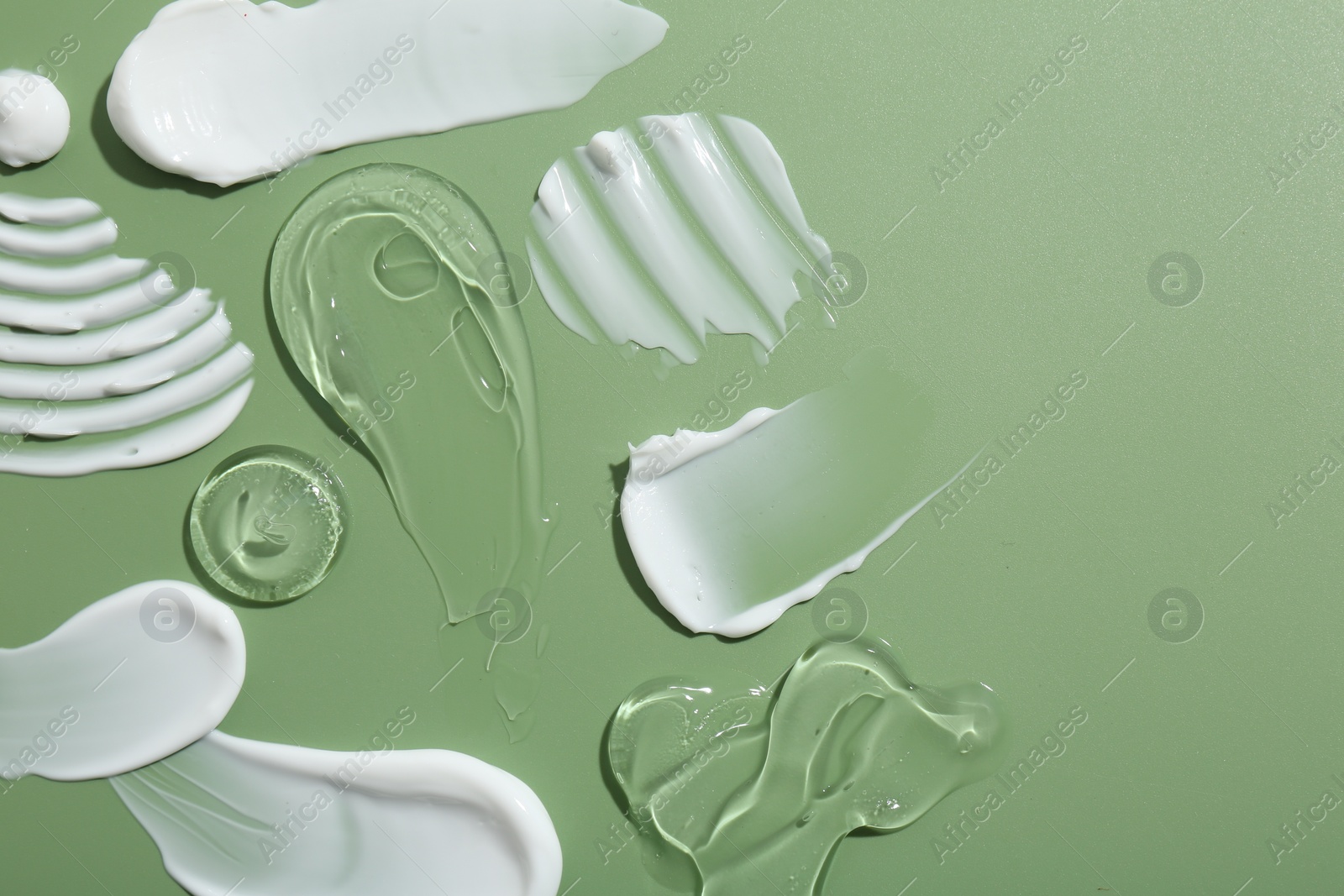 Photo of Samples of face cream on green background, top view. Space for text