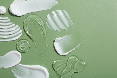 Photo of Samples of face cream on green background, top view. Space for text