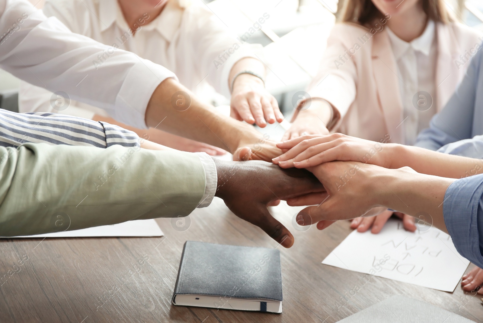 Photo of People putting hands together at table. Unity concept