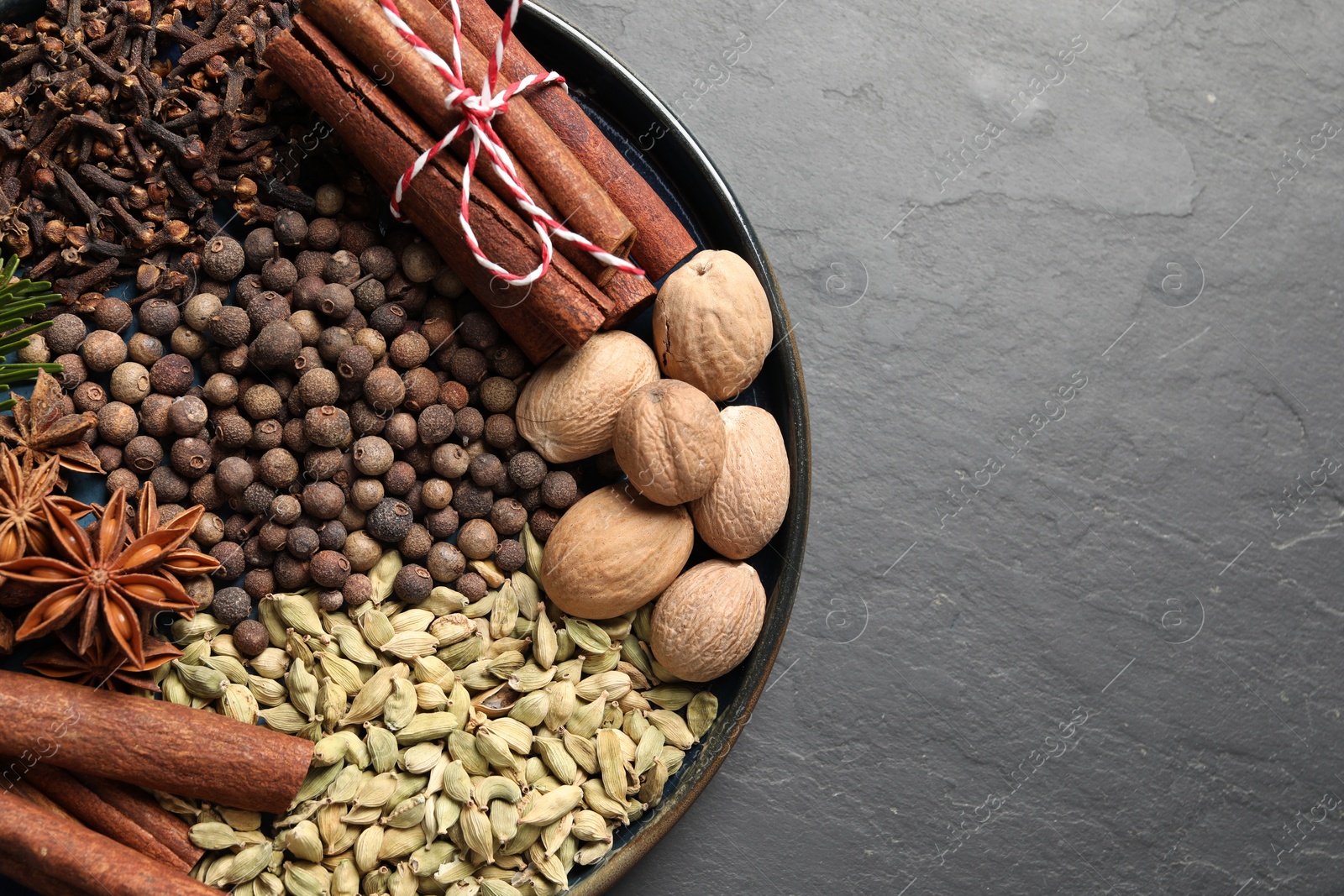 Photo of Different spices and nuts on dark gray textured table, top view. Space for text