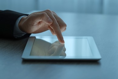 Man using tablet at wooden table, closeup