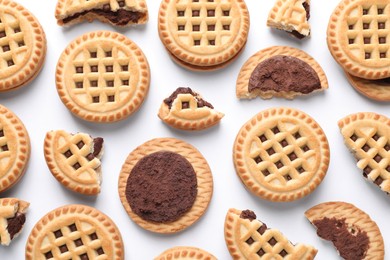 Tasty sandwich cookies with cream on white background, flat lay