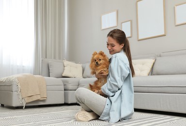 Photo of Happy young woman with cute dog in living room