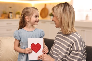 Photo of Little daughter congratulating her mom with greeting card at home. Happy Mother's Day