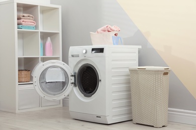 Modern washing machine in laundry room interior