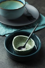 Photo of Set of stylish empty bowls and spoon on grey table