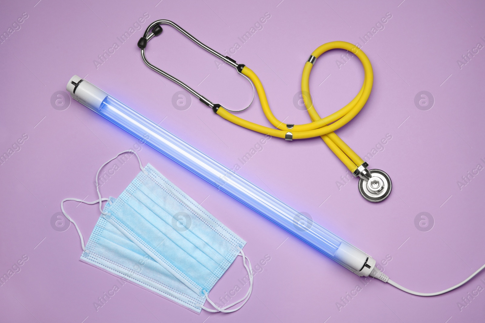 Photo of Flat lay composition with ultraviolet lamp on violet background