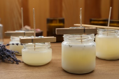 Photo of Glass jars with wax on wooden table, space for text. Handmade candles