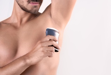 Photo of Young man using deodorant on white background, closeup. Space for text