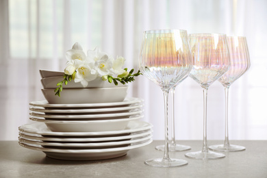 Set of glasses and dishes with flowers on light grey table