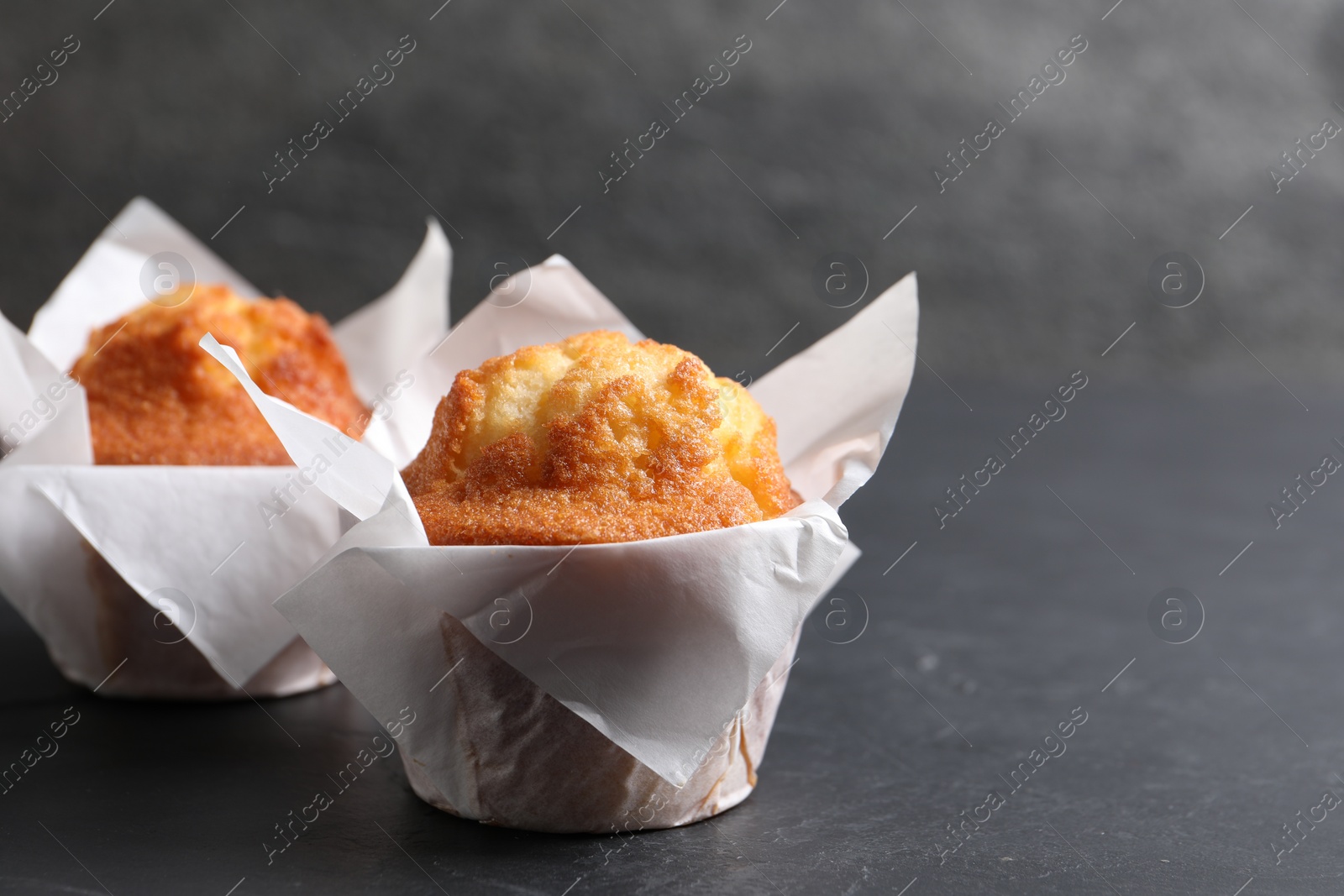 Photo of Tasty muffins on grey table, closeup. Space for text