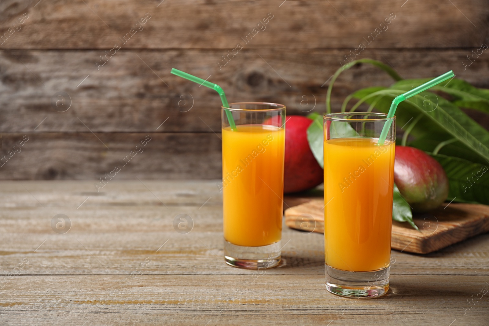 Photo of Fresh delicious mango drink on wooden table. Space for text