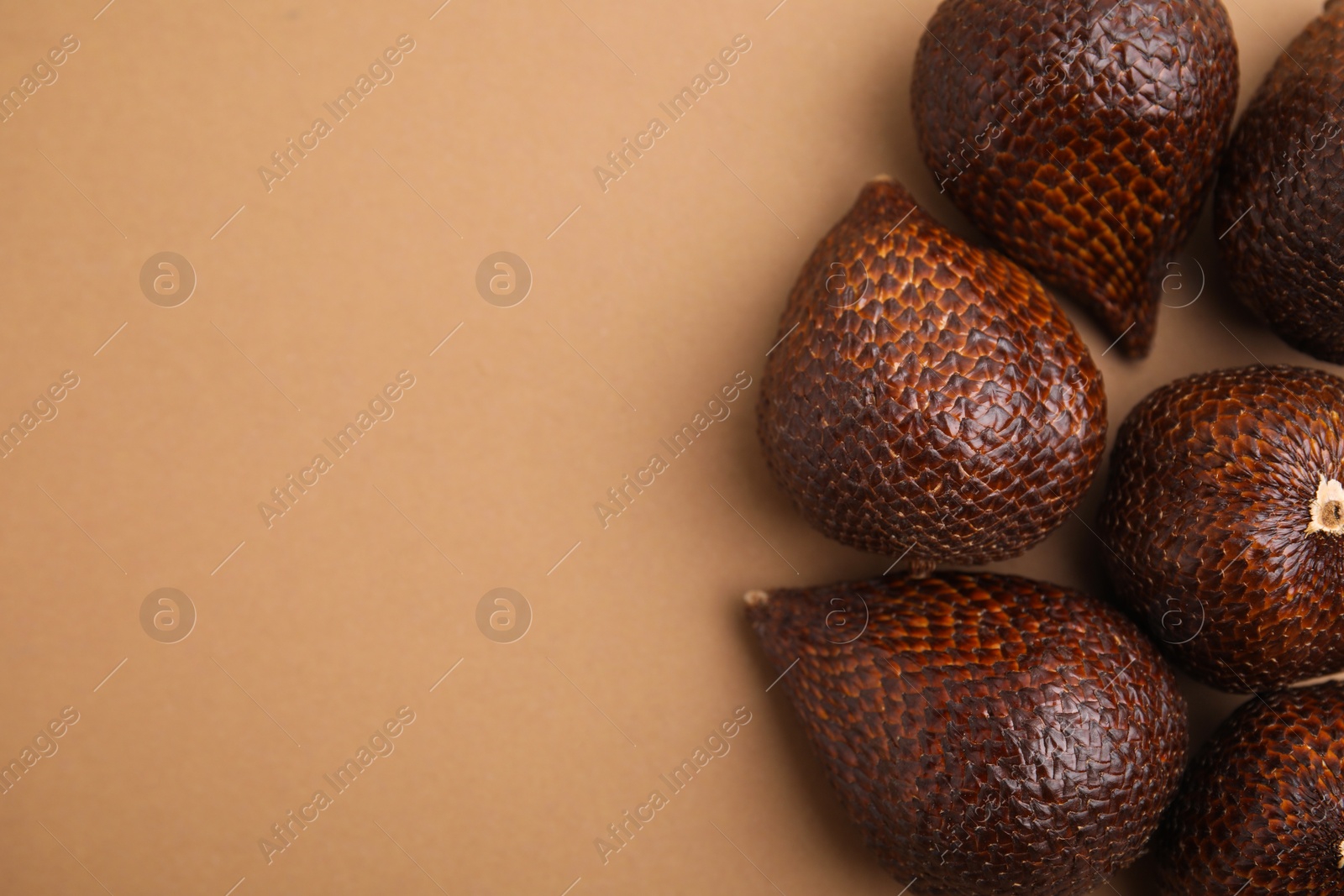 Photo of Delicious salak fruits on pale brown background, above view. Space for text
