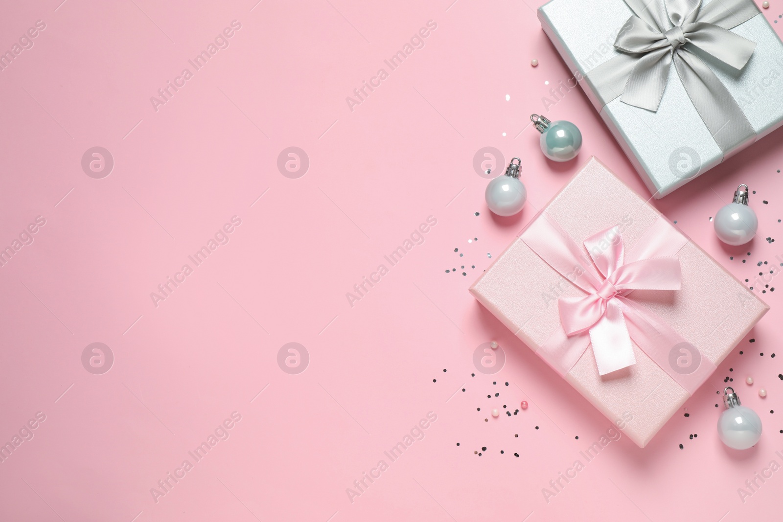 Photo of Beautiful gift boxes, Christmas balls and confetti on pink background, flat lay. Space for text