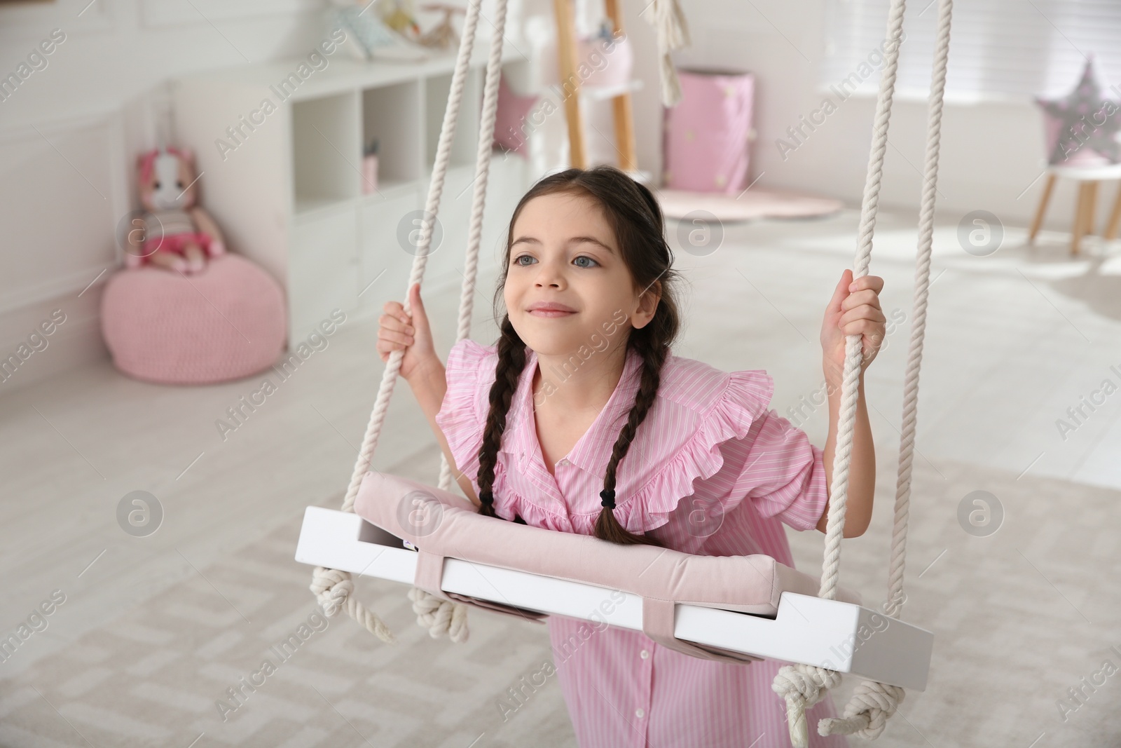 Photo of Cute little girl playing on swing at home