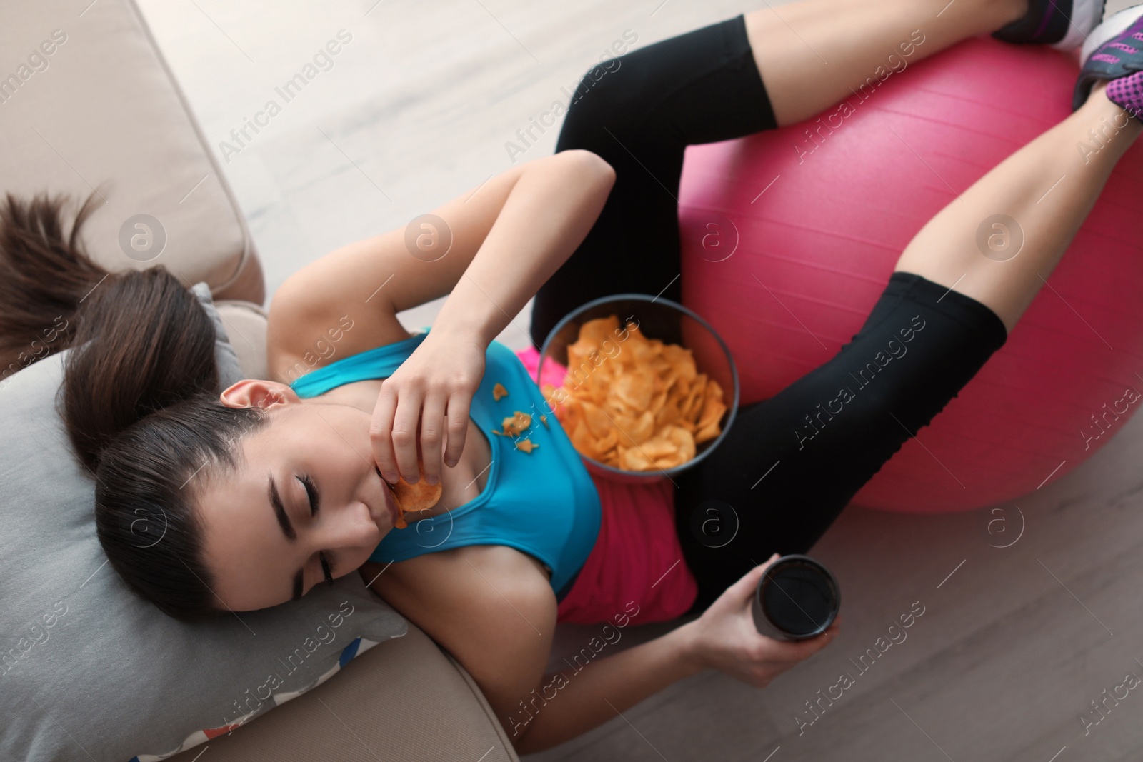 Photo of Lazy young woman eating chips at home, above view