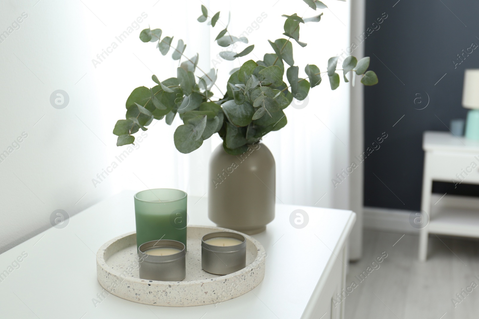 Photo of Candles and eucalyptus branches on white table indoors. Interior element