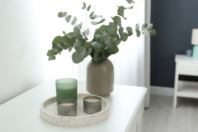 Candles and eucalyptus branches on white table indoors. Interior element