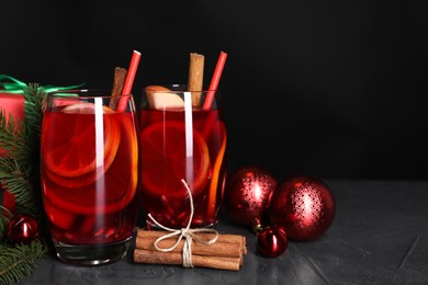 Photo of Delicious Sangria drink in glasses and Christmas decorations on dark textured table, closeup. Space for text