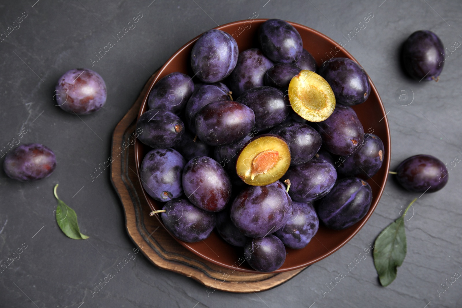 Photo of Delicious ripe plums on black table, flat lay