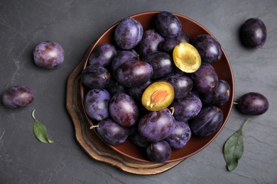 Delicious ripe plums on black table, flat lay