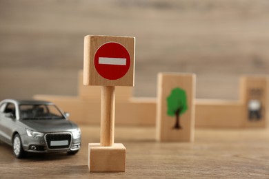 Photo of Traffic sign No entry and toy car on wooden table. Passing driving license exam