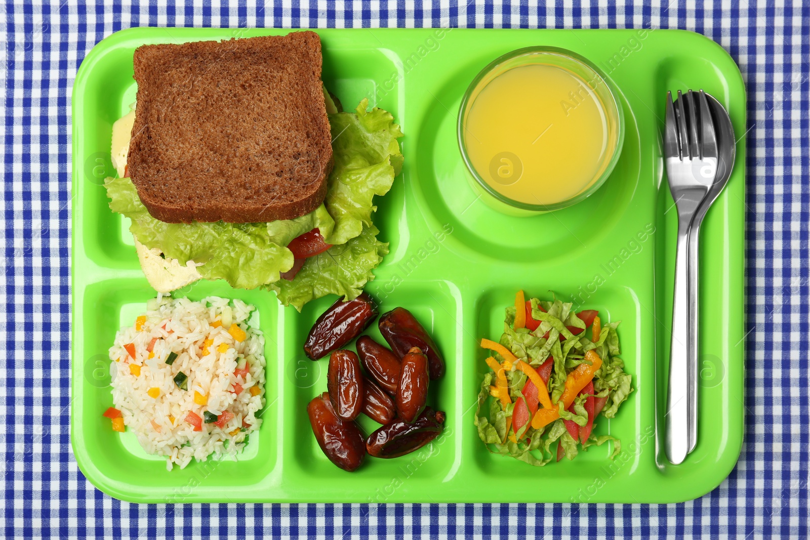 Photo of Serving tray with healthy food on tablecloth, top view. School lunch