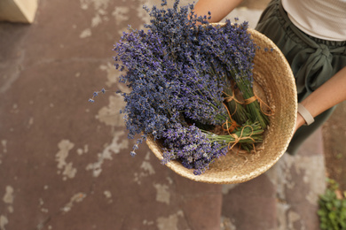 Photo of Woman with basket of beautiful lavender flowers outdoors, closeup