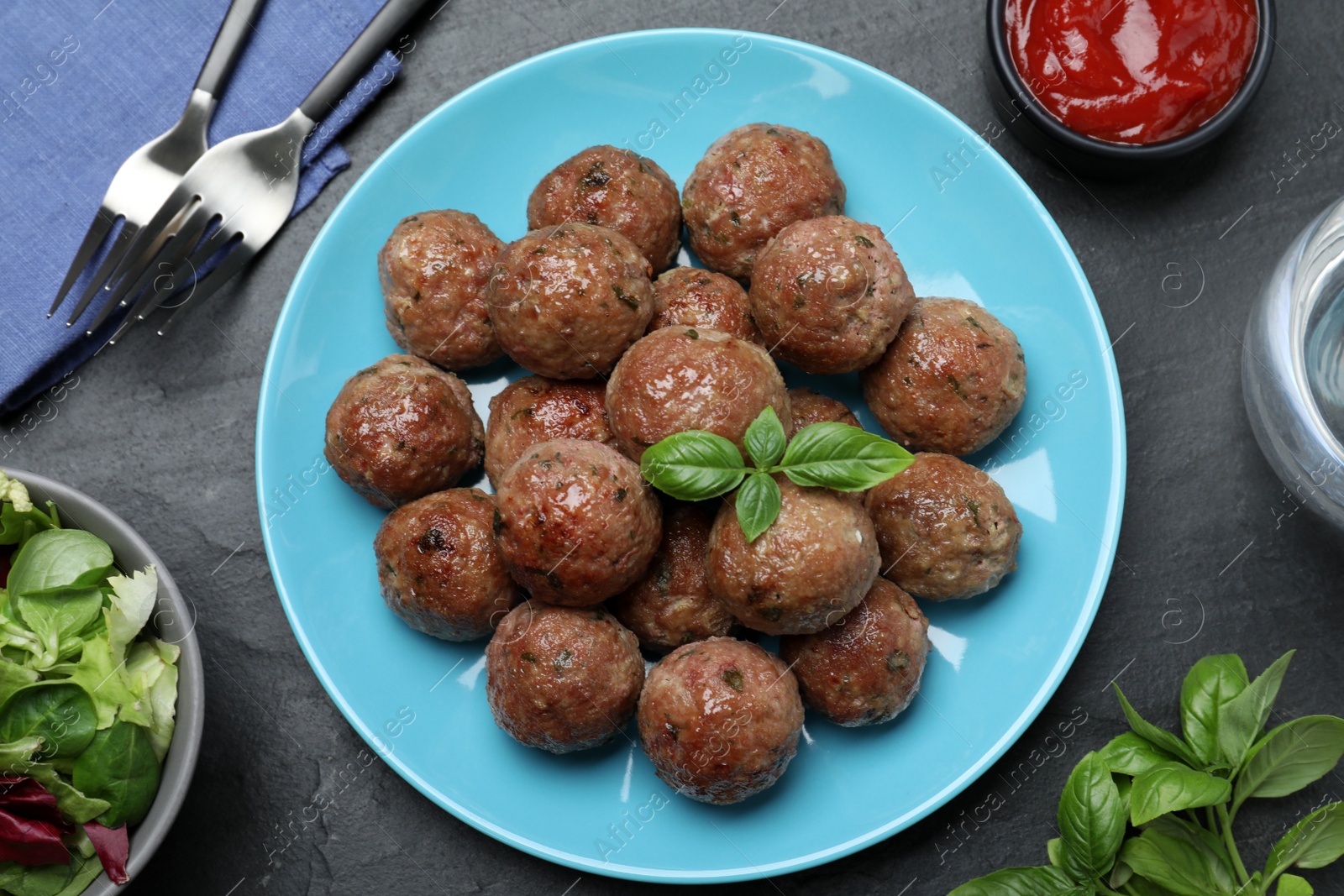 Photo of Tasty cooked meatballs with basil served on black table, flat lay