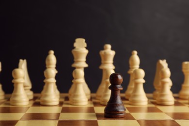 Photo of Black piece among white ones on chess board. Concept of racism
