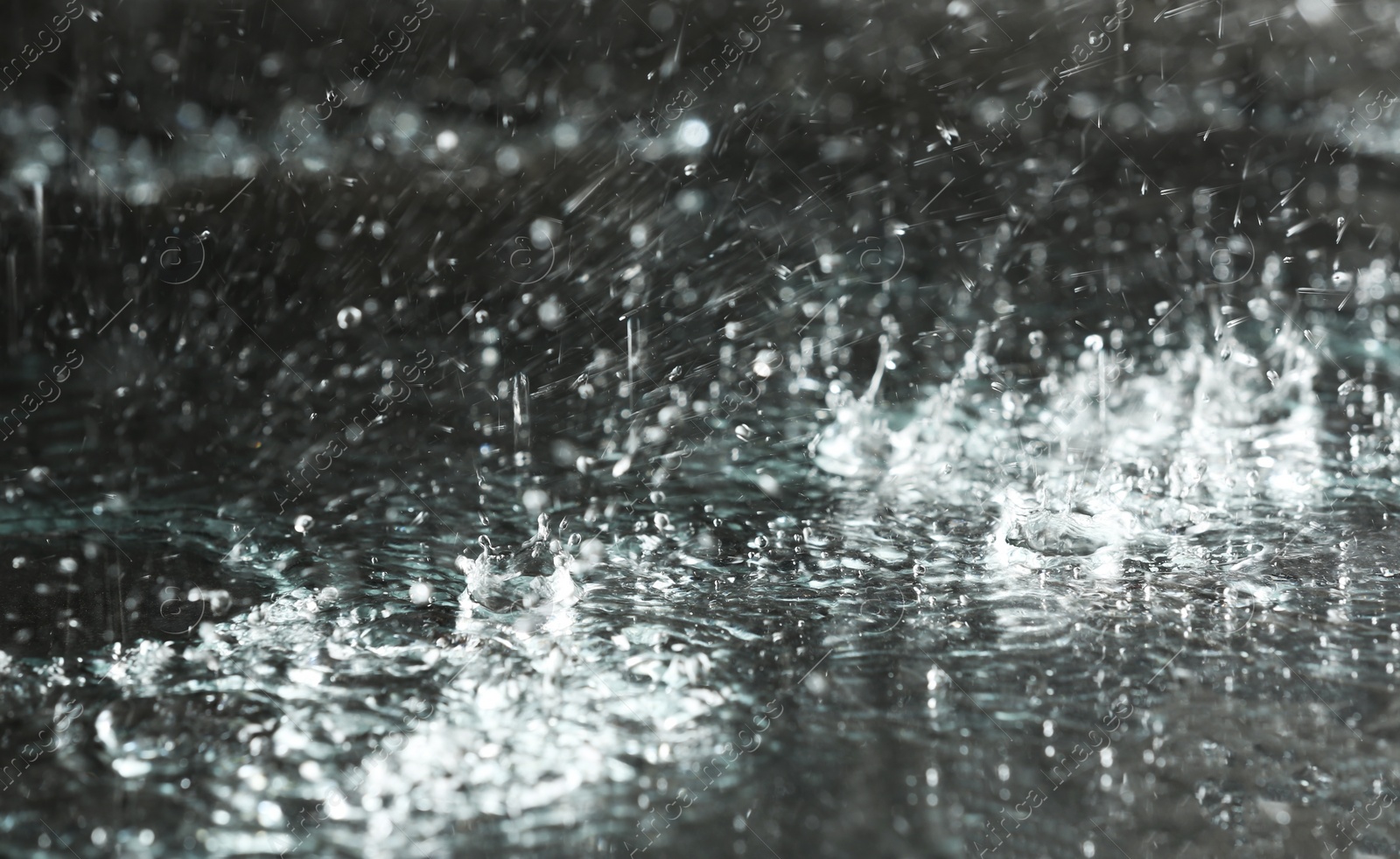 Photo of Heavy rain falling down on ground against dark background