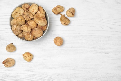 Photo of Bowl of dried figs on wooden table, top view with space for text. Healthy fruit