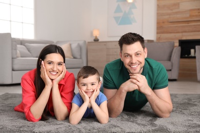 Happy parents and their son lying together on floor at home. Family weekend