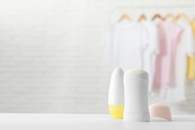 Photo of Different deodorants on white table in room. Space for text